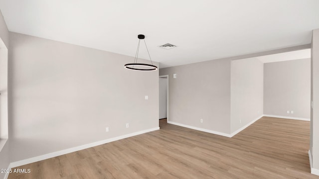 unfurnished room featuring light wood-style floors, visible vents, and baseboards