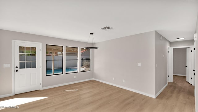 unfurnished dining area featuring baseboards, visible vents, and light wood finished floors