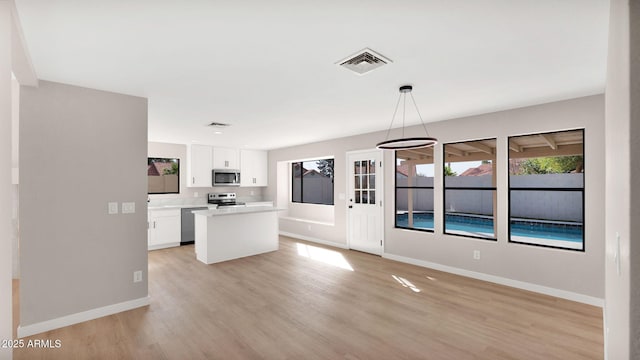 kitchen with light wood finished floors, visible vents, appliances with stainless steel finishes, white cabinetry, and baseboards