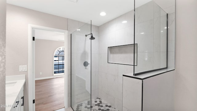 full bathroom featuring wood finished floors, vanity, baseboards, and walk in shower