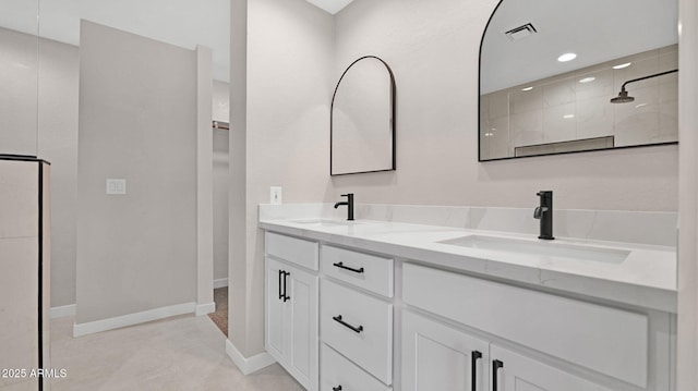 bathroom featuring double vanity, visible vents, a walk in shower, and a sink