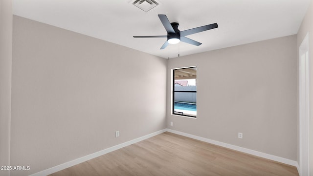 spare room with a ceiling fan, visible vents, light wood finished floors, and baseboards