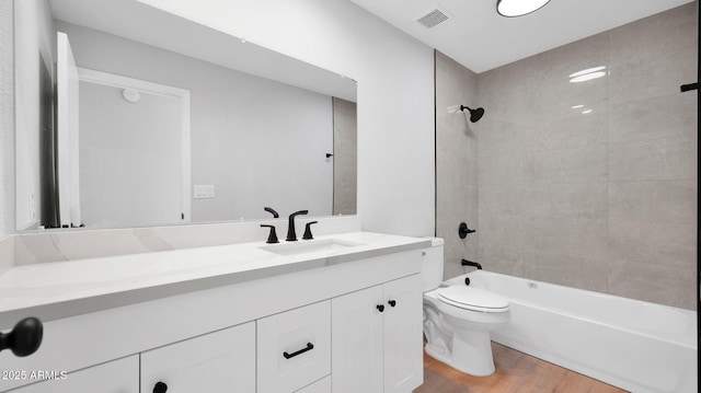 bathroom featuring visible vents, toilet, washtub / shower combination, vanity, and wood finished floors