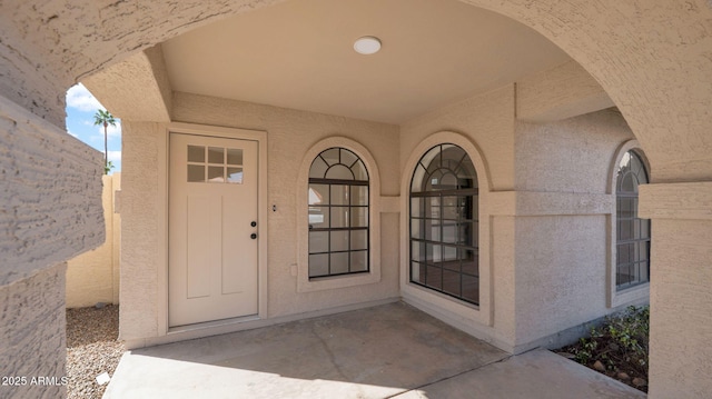 view of exterior entry featuring a patio area and stucco siding