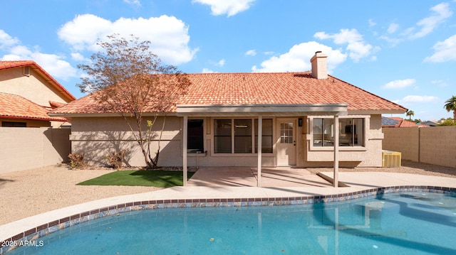 rear view of property with a fenced in pool, a tile roof, and stucco siding