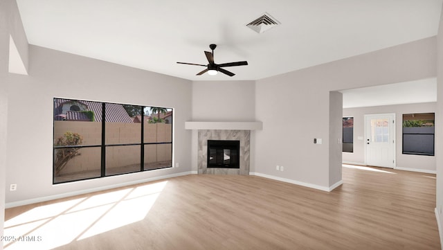 unfurnished living room with light wood-style flooring, a fireplace, visible vents, and a wealth of natural light