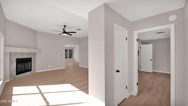 unfurnished living room with visible vents, ceiling fan, light wood-style flooring, and a high end fireplace