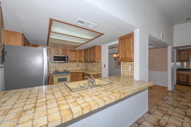 kitchen with appliances with stainless steel finishes, tasteful backsplash, kitchen peninsula, and sink