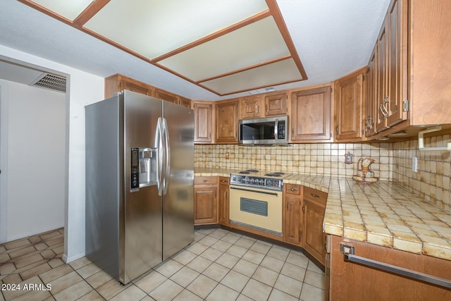 kitchen featuring tile counters, appliances with stainless steel finishes, and tasteful backsplash