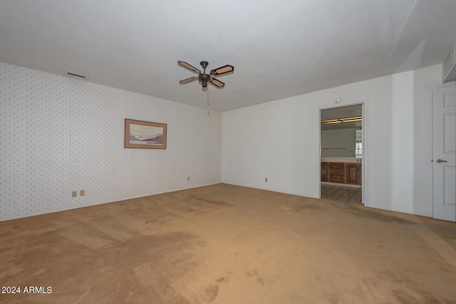 unfurnished bedroom with a walk in closet, ceiling fan, carpet, and ensuite bath