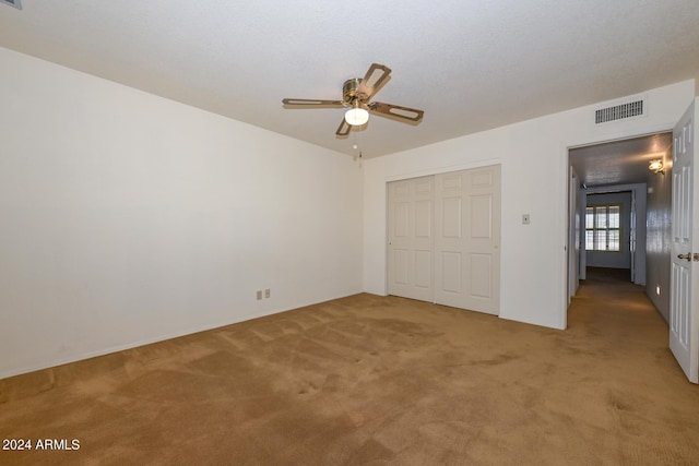 unfurnished bedroom with light carpet, ceiling fan, and a closet