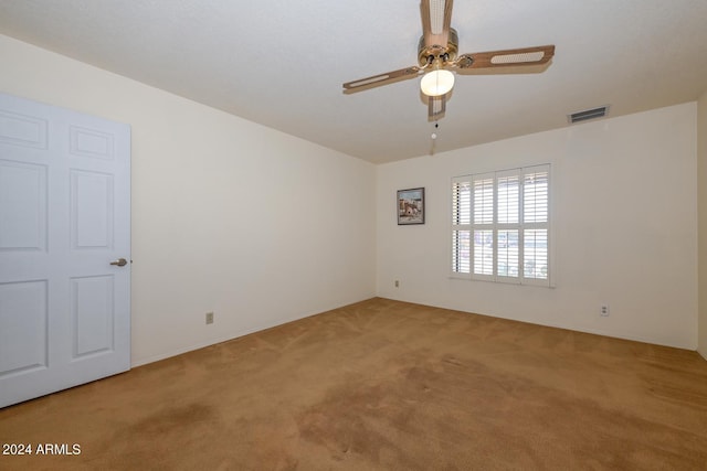 spare room with ceiling fan and light carpet