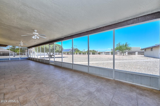 unfurnished sunroom featuring ceiling fan