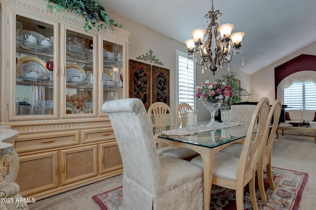 dining room featuring light colored carpet, lofted ceiling, and a chandelier