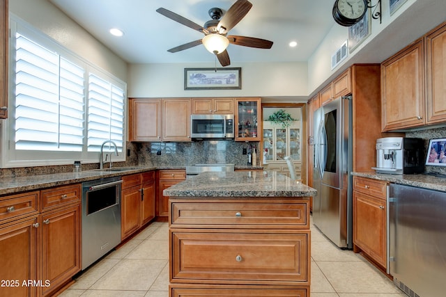 kitchen with a sink, decorative backsplash, appliances with stainless steel finishes, and light tile patterned floors