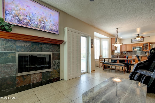 living room with light tile patterned flooring, ceiling fan, and a textured ceiling