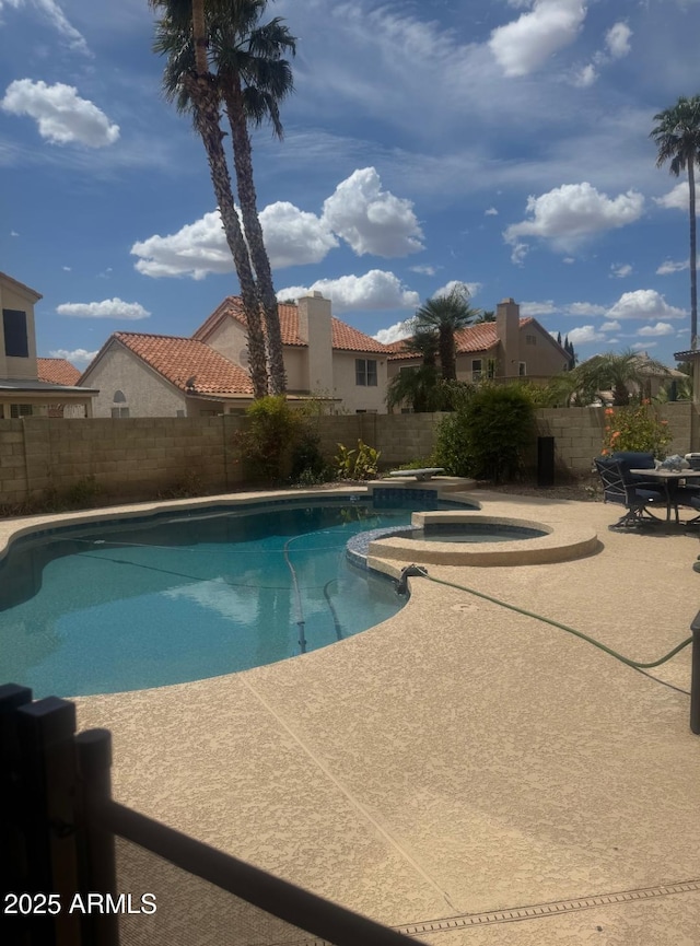 view of pool featuring a patio, a fenced backyard, and a pool with connected hot tub