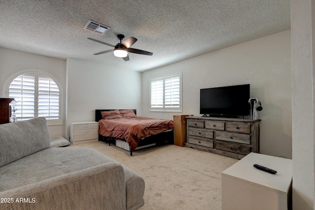 bedroom with visible vents, a ceiling fan, a textured ceiling, and light carpet