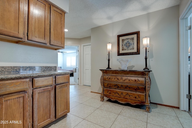kitchen featuring brown cabinets, light tile patterned flooring, a textured ceiling, recessed lighting, and baseboards