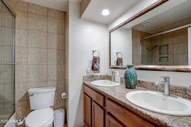 full bath with double vanity, a sink, a tile shower, and toilet
