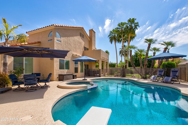 view of swimming pool with a patio, a diving board, fence, and a pool with connected hot tub