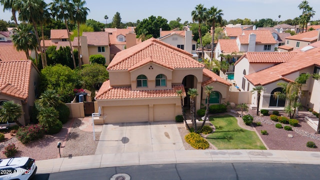 mediterranean / spanish-style home featuring an attached garage, stucco siding, a tile roof, and a residential view
