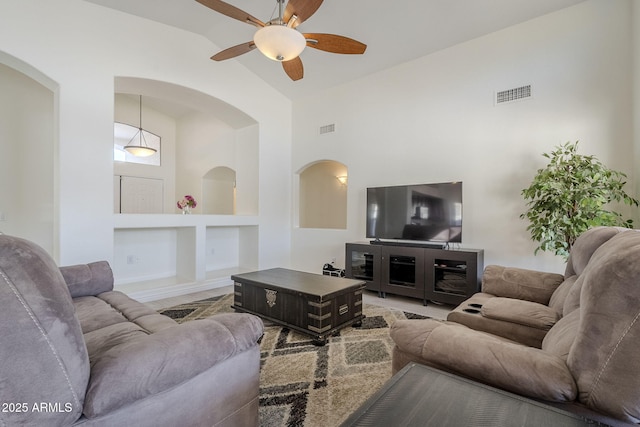 living area with built in features, visible vents, high vaulted ceiling, and a ceiling fan