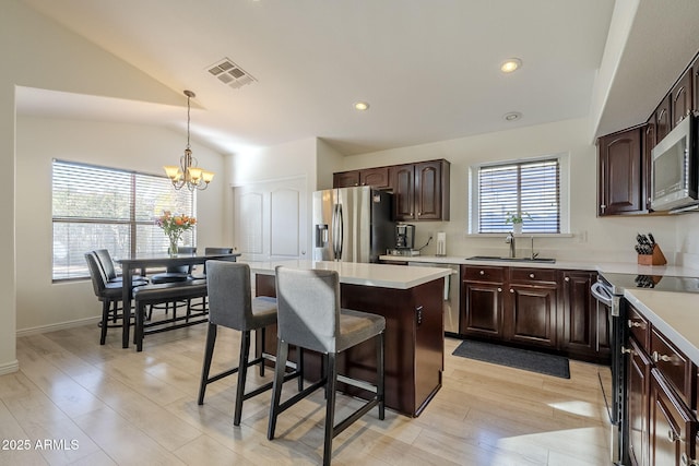 kitchen with appliances with stainless steel finishes, a center island, light countertops, and visible vents