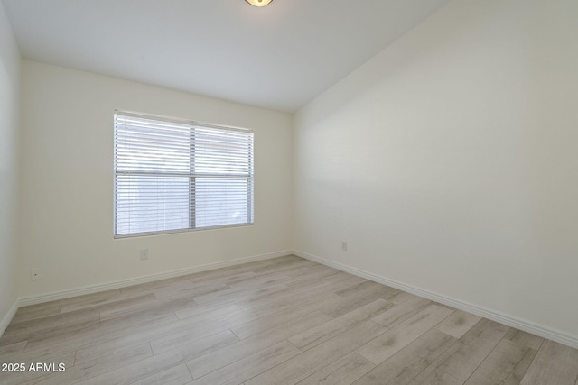 unfurnished room featuring baseboards, lofted ceiling, and light wood-style floors