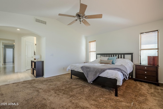 bedroom with arched walkways, carpet, lofted ceiling, visible vents, and a ceiling fan