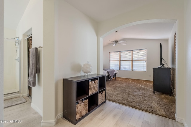 corridor featuring vaulted ceiling, arched walkways, and wood finished floors