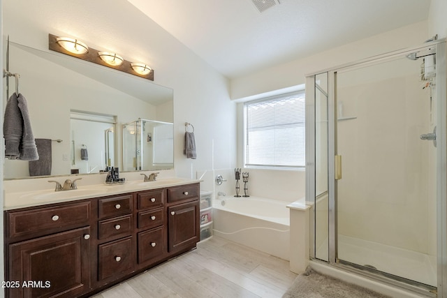 full bath with double vanity, a stall shower, a sink, vaulted ceiling, and a bath