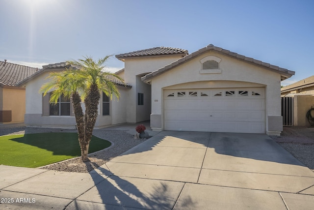 mediterranean / spanish house featuring a garage, concrete driveway, a tile roof, and stucco siding