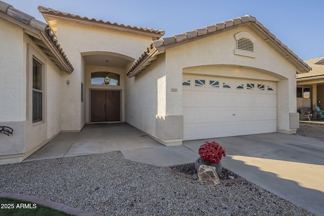 exterior space with a garage, a tile roof, driveway, and stucco siding