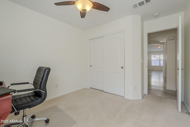 office area featuring baseboards, a ceiling fan, visible vents, and light colored carpet