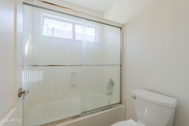 bathroom with toilet and bath / shower combo with glass door