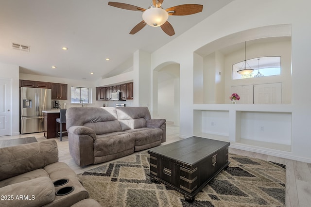 living room featuring light wood-style flooring, recessed lighting, visible vents, built in features, and vaulted ceiling