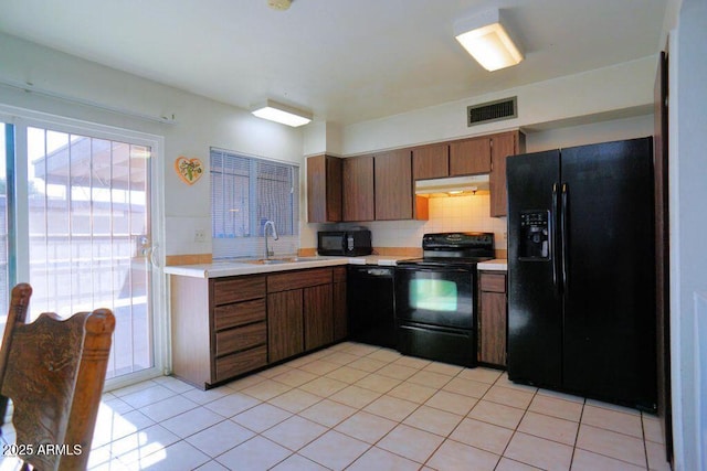 kitchen with visible vents, light countertops, under cabinet range hood, a sink, and black appliances