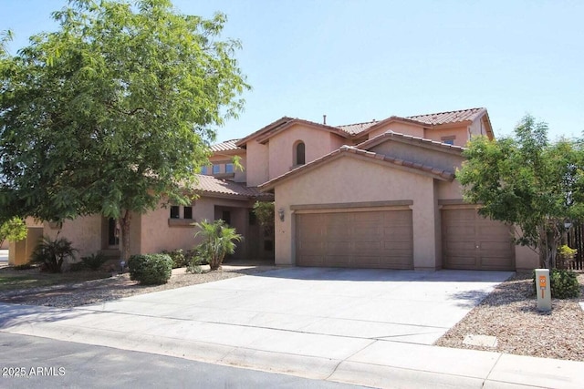 mediterranean / spanish home with an attached garage, stucco siding, a tile roof, and concrete driveway