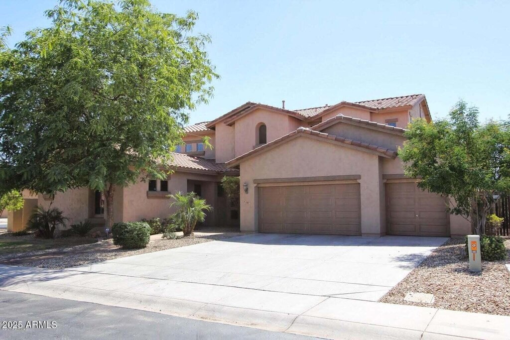 mediterranean / spanish home with an attached garage, stucco siding, a tile roof, and concrete driveway