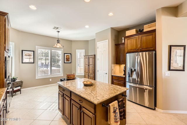 kitchen featuring a center island, hanging light fixtures, stainless steel fridge, light stone countertops, and light tile patterned floors