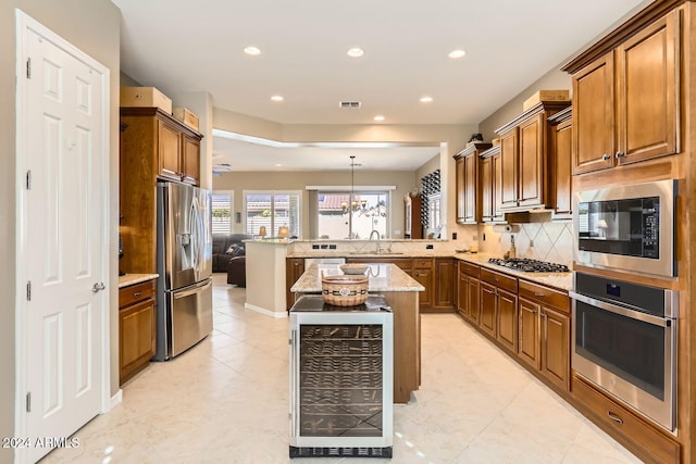 kitchen featuring kitchen peninsula, light stone countertops, stainless steel appliances, a kitchen island, and hanging light fixtures