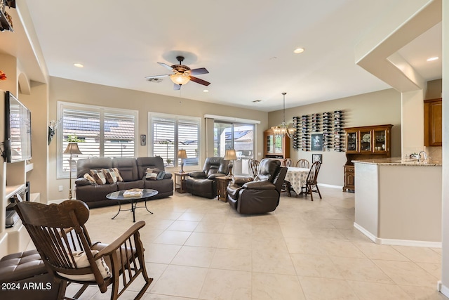 tiled living room with ceiling fan with notable chandelier