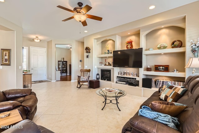 living room with ceiling fan, built in features, and light tile patterned floors