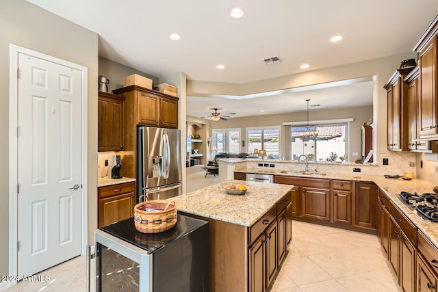 kitchen featuring sink, decorative light fixtures, a kitchen island, ceiling fan with notable chandelier, and appliances with stainless steel finishes