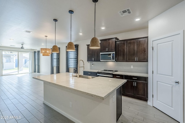 kitchen featuring appliances with stainless steel finishes, a sink, visible vents, and decorative backsplash