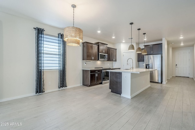 kitchen featuring light wood-style flooring, dark brown cabinetry, stainless steel appliances, light countertops, and backsplash