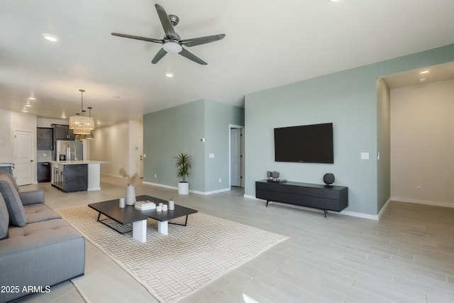 living area with recessed lighting, baseboards, and ceiling fan with notable chandelier