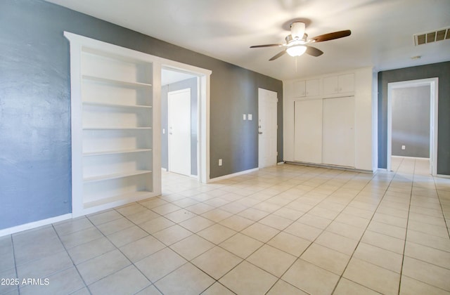 tiled spare room with built in shelves and ceiling fan