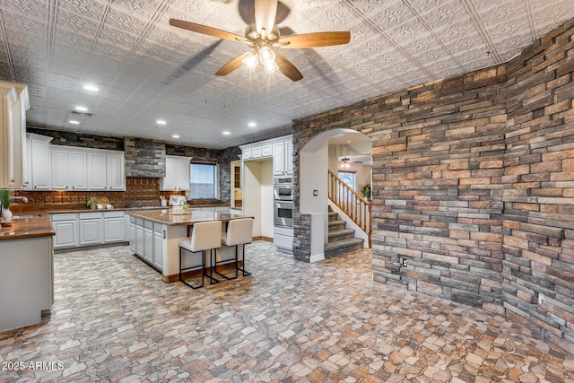 kitchen featuring a kitchen island, white cabinetry, sink, a breakfast bar area, and ceiling fan